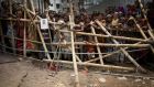 Curious onlookers and relatives of missing victims watch from behind a makeshift fence as workers start dislodging parts of the garment factory building which collapsed in Savar, near Dhaka, Bangladesh. Photograph: Wong Maye-E/AP 