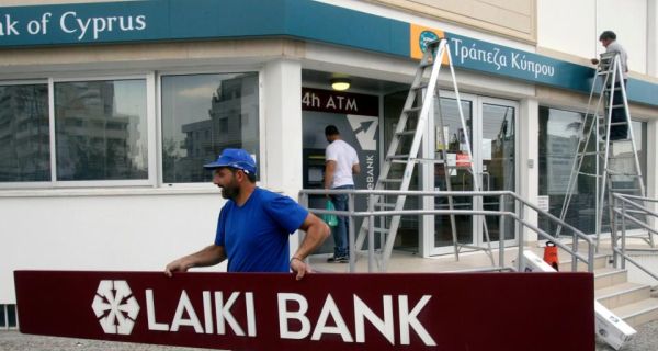 Workers remove signs from a branch of Laiki Bank in Nicosia.  Photograph: Andreas Manolis/Reuters