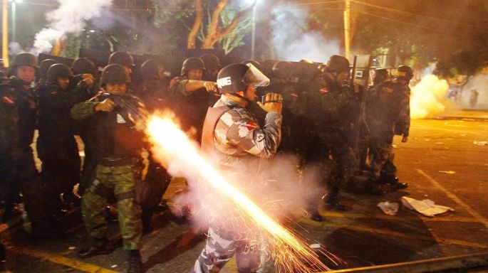 A riot policeman fires his weapon while confronting stone-throwing demonstrators during an anti-government protest in Belem. Photograph: Ney Macondes/Reuters