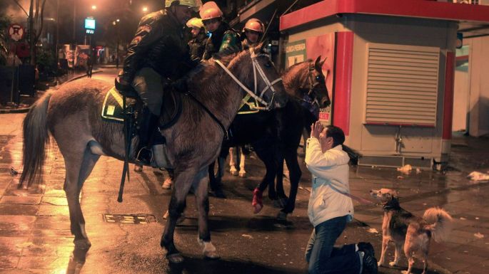 A woman kneels in front of mounted riot policemen in Porto Alegre. Photograph: Gustavo Vara/Reuters