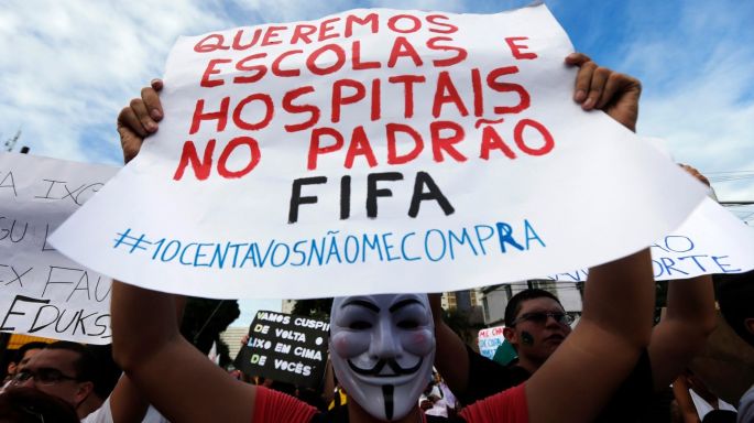 A demonstrator wearing a Guy Fawkes mask holds up a sign during a protest against the Confederations Cup and President Dilma Rousseff's government, in Recife City.  Photograph: Marcos Brindicci/Reuters
