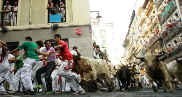 Runners sprint alongside Torrestrella fighting bulls as they take the Estafeta curve during the fifth running of the bulls of the San Fermin festival in Pamplona. Photograph: Susana Vera/Reuters
