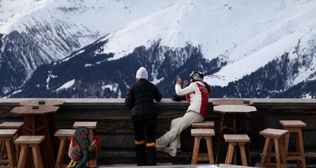 Skiers stop to look over the balcony and down to the town of Davos from the Chalet Gueggel restaurant on the Jakobshorn mountain in Davos, Switzerland. Photograph: Simon Dawson/Bloomberg