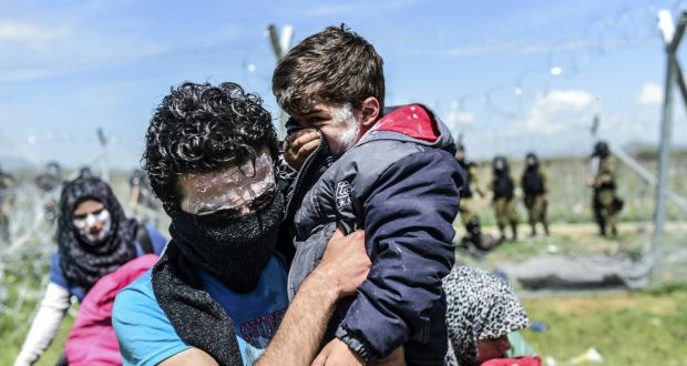 A family with toothpaste smeared over their faces as a protection against tear gas moves to safety as refugees and migrants clash with Macedonian police during a protest near their makeshift camp in the northern Greek border village of Idomeni. Photograph:  Bulent Kilic/AFP/Getty Images