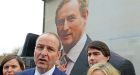 Miche&aacute;l Martin by a poster of Enda Kenny: the formation of governments is essentially a numbers game and the numbers point to an FG-FF coalition. Photograph: Eric Luke / The Irish Times