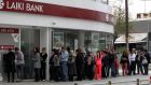 People queue up to make a transaction at an ATM outside a branch of Laiki Bank in Nicosia. 