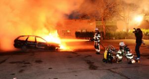 Firefighters extinguish a burning car, following riots in the Stockholm suburb of Kista last night. Photograph: Fredrik Sandberg/Scanpix/Reuters