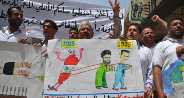 Demonstrators carry a poster depicting a caricature of Syrian president Bashar al-Assad and Lebanon’s Hizbullah leader Sayyed Hassan Nasrallah during a protest in Kafranbel, near Idlib, yesterday. Photograph: Raed al-Fares/Reuters