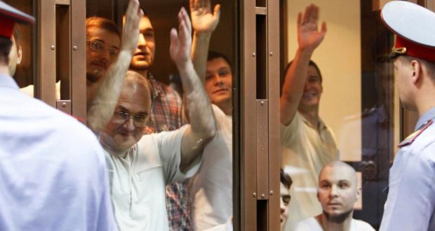 Defendants facing trial over clashes with the police during an anti-Putin protest last year, gesture inside a glass-walled cage before a court hearing in Moscow yesterday. Photograph: Sergei Karpukhin/Reuters