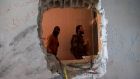 Free Syrian Army fighters are pictured through a hole in a wall in Deir al-Zor. Phootgraphh: Khalil Ashawi/Reuters