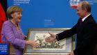 Russia’s president Vladimir Putin presents a historical lithograph to Germany’s chancellor Angela Merkel after their meeting at the St Petersburg International Economic Forum in St Petersburg, Russia, today. Photograph: Alexander Demianchuk/Reuters