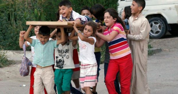 Children pretend to  carry a coffin as they play along a street in Raqqa province, eastern Syria. Photograph: Nour Fourat/Reuters