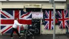 A woman walks past a union flag attached to a shuttered shopfront on the Shankill Road in west Belfast last  December following violent protests over restrictions on flying the flag from Belfast City Hall. “If anyone is in any doubt about how conflict disrupts business, just ask Belfast’s hard-pressed merchants.” Photograph: Reuters