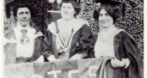 Hanna Sheehy Skeffington, Kathleen Shannon, and Kate Sheehy, in thier graduation robes and mortar boards, carrying a banner demanding votes for women. 