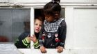 Two Roma children lean out through the  window of a caravan at an encampment of Roma families in Triel-sur-Seine, near Paris. Photograph: Benoit Tessier/Reuters