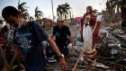  Residents walk past a statue of Jesus Christ in the rubble of a neighbourhood  in Tacloban that was devastated by Typhoon Haiyan.  Photograph: Kevin Frayer/Getty Images