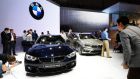 Visitors look at a BMW 218d Active Tourer SUV automobile, right, and a BMW 435i Gran Coupe automobile as they stand on display at the company’s stand on the opening day of the 84th Geneva International Motor Show in Geneva.