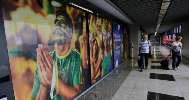 People arrive past a large banner with images of Brazil fans at the international airport in Curitiba. Photograph: Reuters