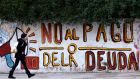 A woman walks past a graffiti that reads “No to the debt payment” in Buenos Aires. Photograph: Marcos Brindicci/Reuters