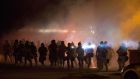Riot police move to clear demonstrators from a street in Ferguson, Missouri, last night. Police  fired  tear gas to disperse protesters  on the fourth night of demonstrations over the fatal shooting last weekend of an unarmed black teenager, Michael Brown. Photograph: Mario Anzuoni/Reuters