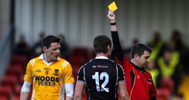 Kilcoo’s Paul Devlin gets a yellow card from referee Noel Mooney during the Ulster club clash at Páirc Esler. Photo: Russell Pritchard/Presseye/Inpho