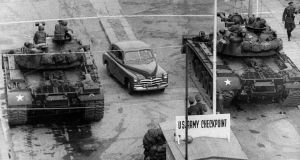 An armoured water truck cleans the street of debris after the East German government ordered construction work to strengthen the border crossing at Heinrich-Heine- Strasse (aka Checkpoint Delta) on the Berlin Wall, December 4th, 1961 A car drives between US tanks, in October 1961, across the famous borderof the US sector in Berlin, at Checkpoint Charlie crossing point which was used by diplomats and foreigners