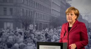 German Chancellor Angela Merkel gives her speech today in front of a photograph depicting the opening of the inner-city border at Bernauer Strasse in 1989. Photograph: Soeren Stache/EPA