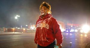 A demonstrator walks down the street in Ferguson, Missouri, November 24th 2014, after suffering the effects of teaar gas following the grand jury decision not to indict police officer Darren Wilson for shooting dead  Michael Brown in August. Photograph: EPA/Larry W Smith