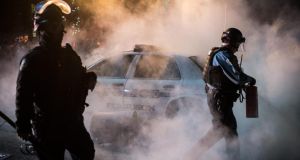Policemen extinguish a fire burning a police vehicle near the Ferguson City Hall, in Ferguson, Missouri. Photograph: Alexey Furman/EPA.