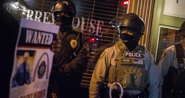 Protesters holding an image of officer Darren Wilson walk past police guarding a business in Ferguson, Missouri on November 29th. Photograph: Adrees Latif/Reuters