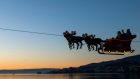  Santa Claus waves to the crowd from his flying sleigh. Photograph: Jean-Christophe Bott/EPA
