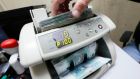 An employee uses a machine while counting Russian ruble banknotes at a private company’s office in Krasnoyarsk, Siberia.