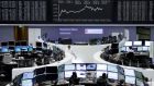 Traders work at their screens in front of the German share price index DAX board at the stock exchange in Frankfurt yesterday. Photograph: Pawel Kopczynski/Reuters