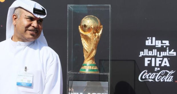 A Qatari official stands beside the Fifa World Cup trophy as part of trophy’s world tour. The Qatar 2022 World Cup looks set to be shortened by a matter of days and held in November-Decemebr.  Photograph: Karim Jaafar/Getty Images