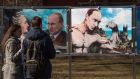 A couple stands by pictures depicting Russian president Vladimir Putin at an open-air political cartoons exhibition dedicated to the one-year anniversary of Crimea voting to leave Ukraine and join the Russian state in central Moscow. Photograph: Dmitry Serebryako/AFP/Getty Images
