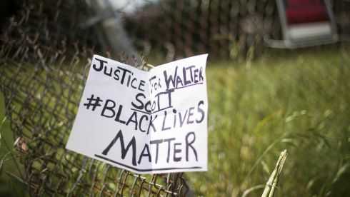 A placard is tied to a fence outside the vacant lot where Walter Scott, the 50-year-old man who was fired at eight times was killed as he ran away from an officer after a traffic stop in North Charleston, South Carolina. Police officer Michael Slager, 33, who fatally shot Scott has been fired after he was charged with murder, the mayor said. Speaking at a highly charged press conference frequently interrupted by residents angered at America's latest high-profile police killing of a black man, Mayor Keith Summey said the city had moved quickly to fire the officer after Saturday's shooting.   Photograph: Jim Watson/AFP
