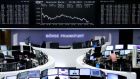 Traders are pictured at their desks in front of the DAX board at the stock exchange in Frankfurt, Germany, yesterday. Photograph: Reuters