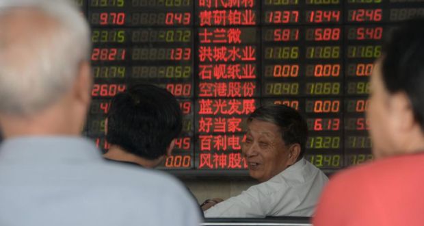 Investors chat in front of an electronic board showing stock information at a brokerage house in Shanghai