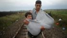  A youth carries a young boy in a makeshift sling as they walk towards waiting buses at the Hungarian border with Serbia. Photograph: Christopher Furlong/Getty Images