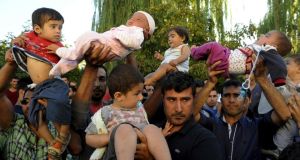 Migrants lift their children as they protest to be allowed to cross into Greece near the Turkish border in Edirne, on Sunday. Photograph: Reuters 