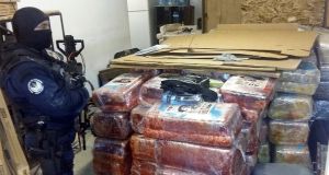 A federal police officer guards packages presumed to contain cannabis, next to the access tunnel discovered by authorities. Photograph: AFP/Getty Images