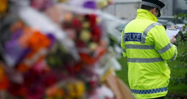 A policeman stands beside floral tributes at the gates of Cults Academy Aberdeen, Scotland. Photograph: Reuters