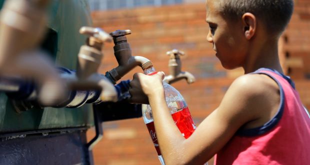 A young boy fills his cup from a water tanker in Coronation, Johannesburg, as South Africa experiences its worst drought in decades. EPA/KIM LUDBROOK