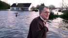 Tom Quinn with his flooded house in the backround at the townland of Caherfurvaus near Craughwell. Photograph: Joe O’Shaughnessy
