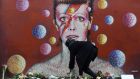  A women lays flowers at a mural of British singer David Bowie in Brixton, birth place of the late David Bowie in London, on Monday. Well-wishers have flocked to the  mural to pay their respects following the announcement of his death. Photograph: EPA 