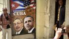 A tourist poses for a picture with a sign placed at the entrance of a restaurant with the images of Cuban and US Presidents Raul Castro and Barack Obama in Havana, Cuba on Saturday. Photograph: AFP/Getty Images  