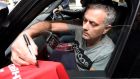 Jose Mourinho signs a Manchester United soccer shirt held out by a fan as he leaves his house in London. Photograph: Toby Melville/Reuters