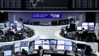 Traders work at their desks in front of the German share price index, DAX board, at the stock exchange in Frankfurt. Reuters