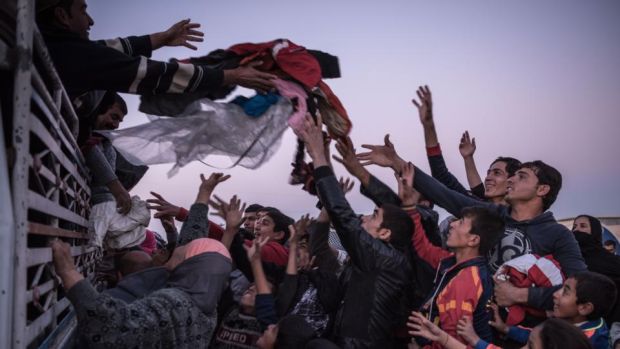 Charity workers distribute clothing to displaced people at the Khazer camp in Iraq. Photograph: Sergey Ponomarev/New York Times