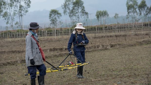 Staff from Mines Advisory Group (MAG) carry a loop detector across a rice field during a demining mission for a local farmer in Phonsavan, northeast Laos. Photograph: Brenda Fitzsimons